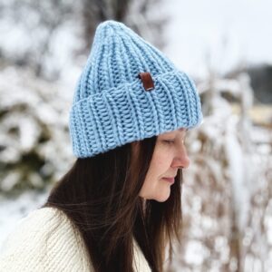 Czapka zaprezentowana od boku na modelce, Kolor błękitny, dziergana ręcznie ze 100% wełny.