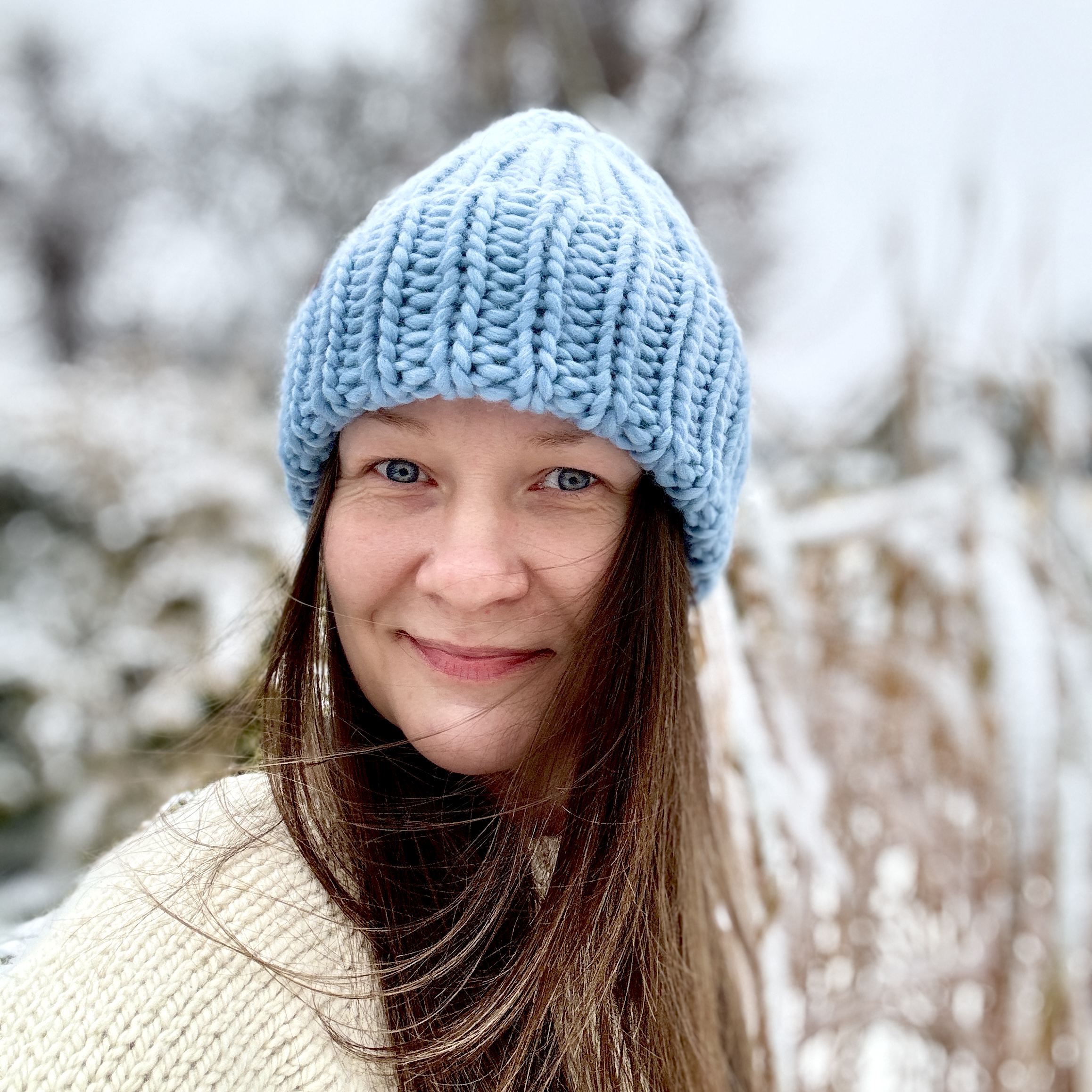 Prezentacja na modelce od przodu czapki z wełny, wykonanej ręcznie w kolorze niebieskim jasnym.