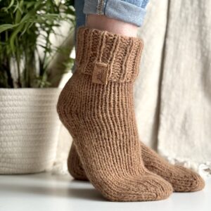 Brązowe, grube, ręcznie dziergane skarpety na stopie modelki