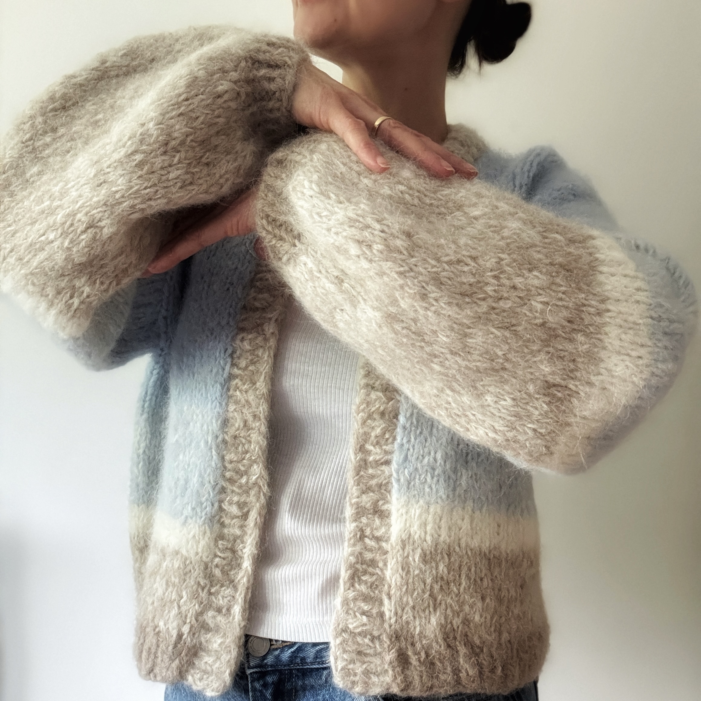 Detal, rękawy kardiganu handmade z wełny alpaki w trzech kolorach - niebieskim, beżowym i śmietankowym.
