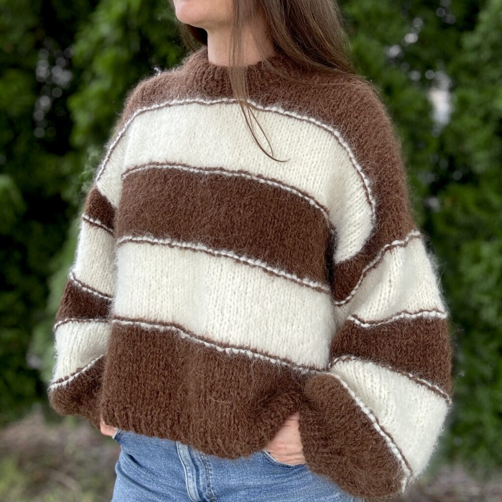 Sweter w śmietankowo-czekoladowe paski z alpaki, prezentowany na modelce, wykonany ręcznie na drutach z miękkiej wełny alpaki i merynosa.